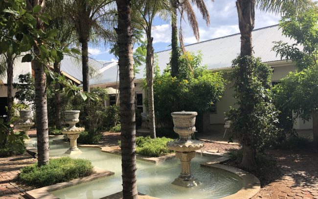 Cour intérieure du lodge Out of Africa en Namibie avec fontaine et palmiers
